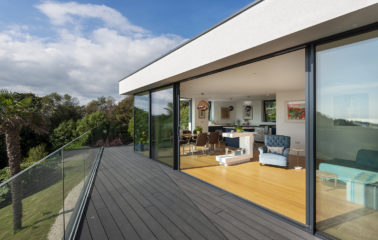 Floor to ceiling glazing captures panoramic sunsets and maritime pines outside.