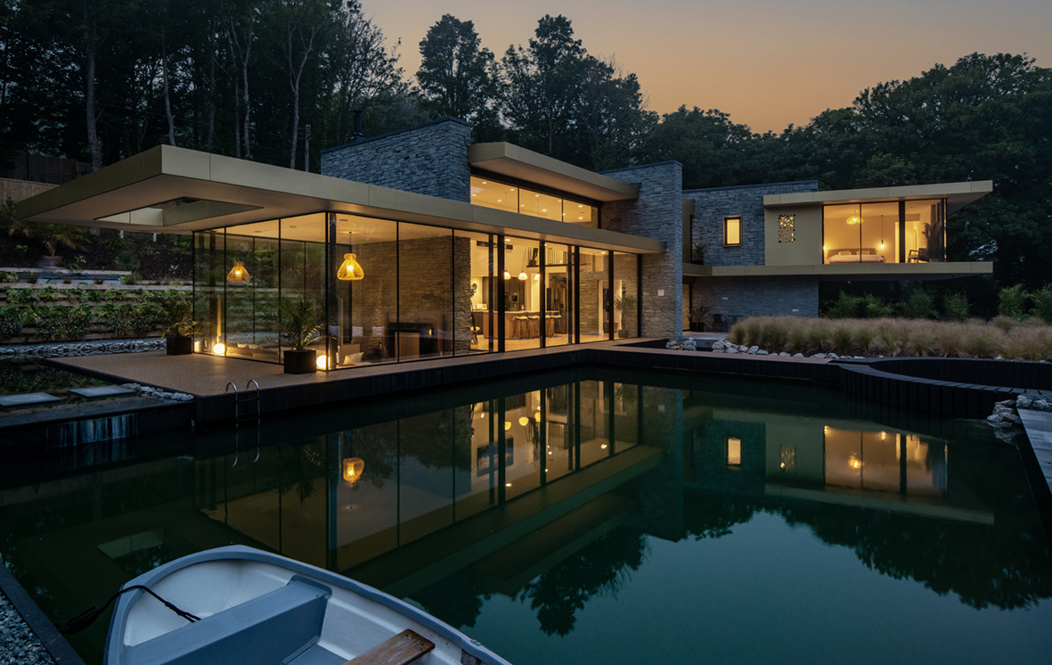 A view at dusk of the amazing California-style glass house with black sliding doors