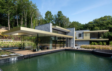 Black sliding doors for glass house overlooking a natural pool
