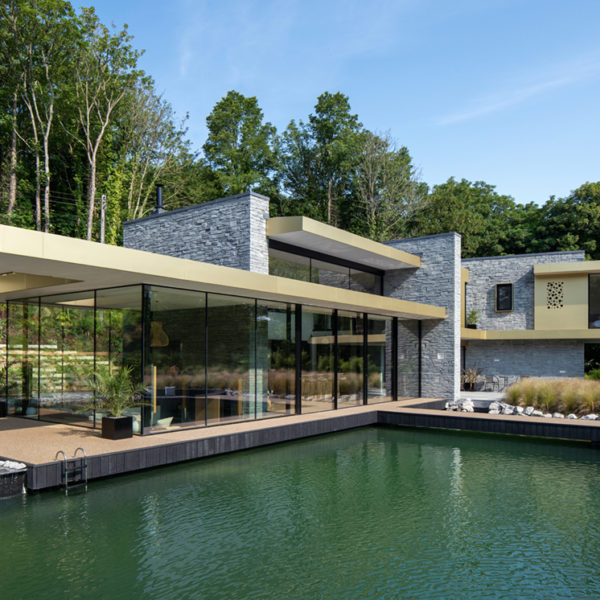Black sliding doors for glass house overlooking a natural pool