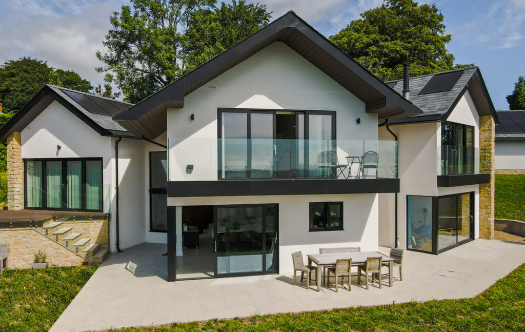 View of house with first floor sliding dooors with glass balustrade balcony